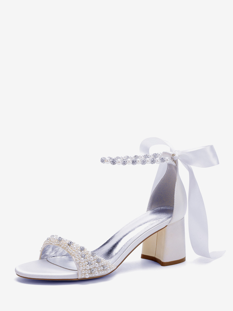 Chaussures de mariée blanches à bout ouvert ornées de perles et de strass avec bride à la cheville et talon compensé.